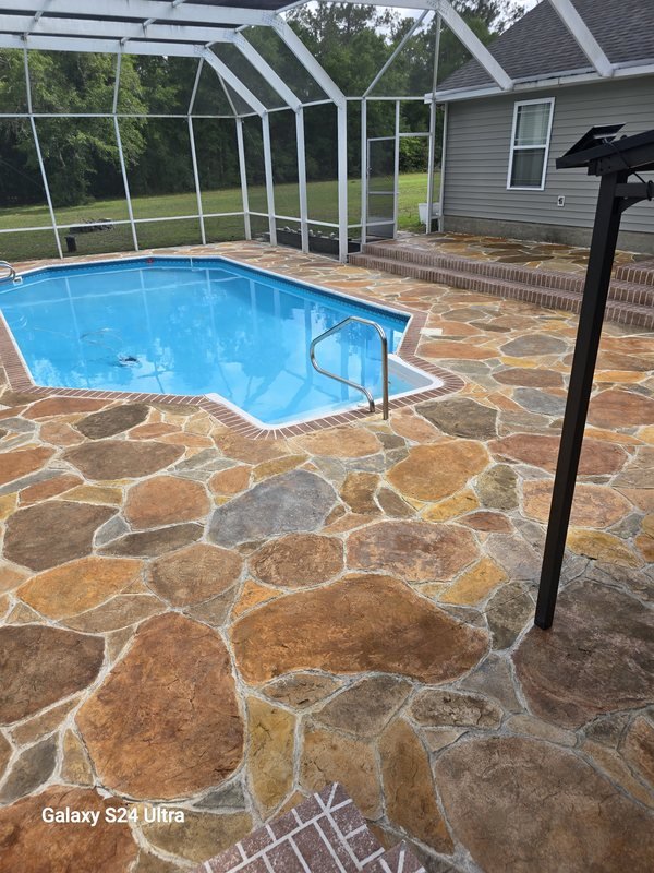 Multi-color flagstone pool deck inside a screened enclosure with a brick paver border