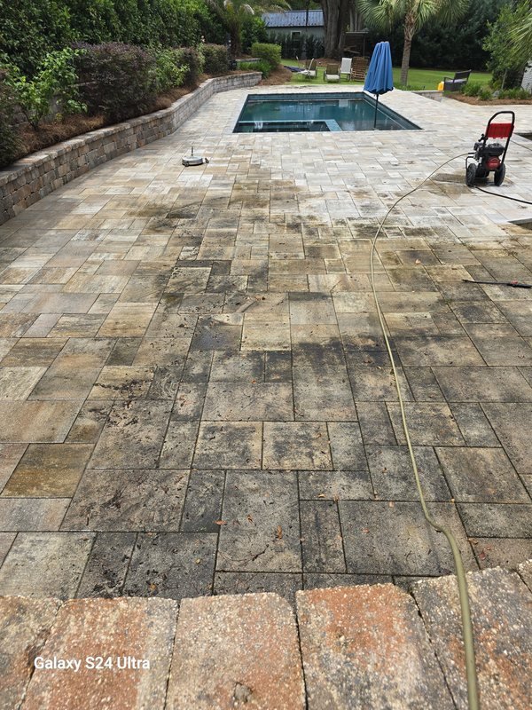 Freshly cleaned travertine paver pool deck with a raised planter wall and pool in the background