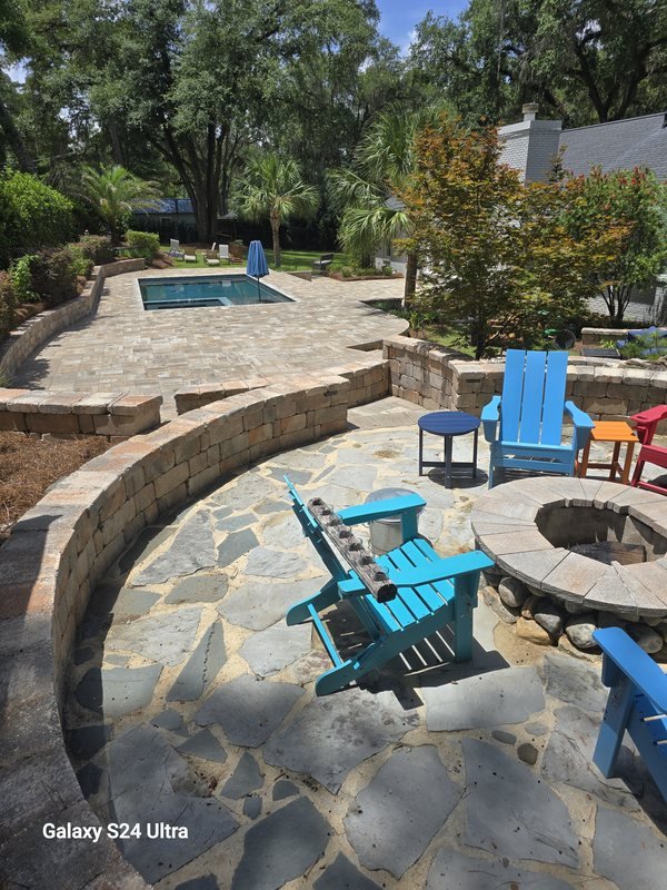 Curved flagstone patio with a stone fire pit, curved seat wall, and Adirondack chairs